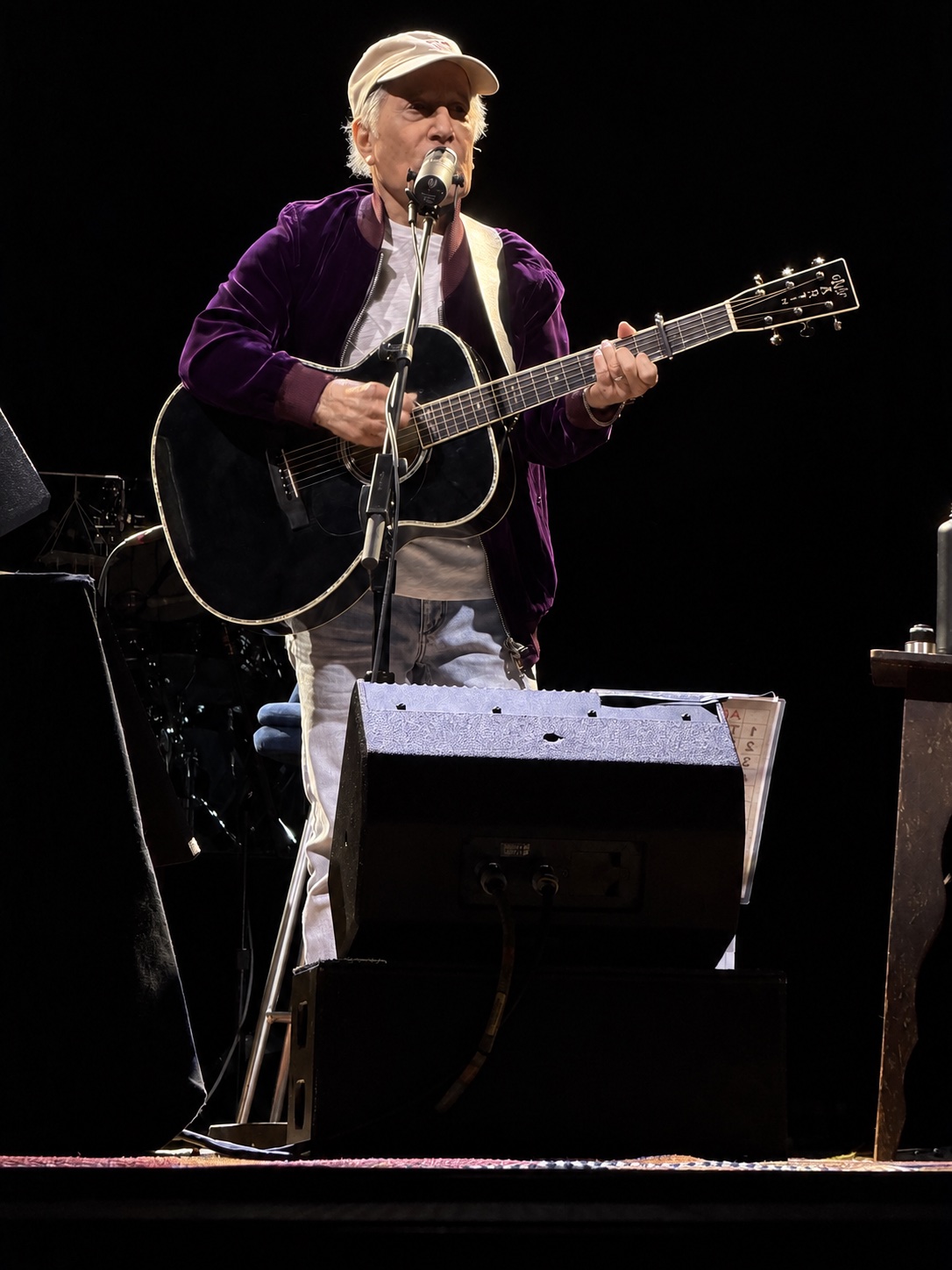 Paul Simon performing with an acoustic guitar in Amsterdam